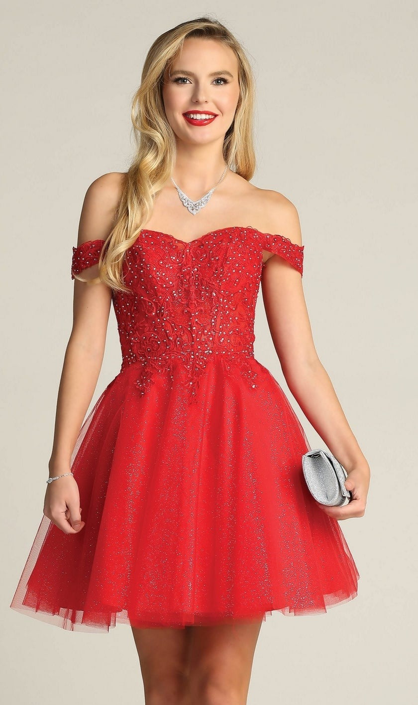 A woman in the Off-Shoulder Short Glitter Homecoming Dress C318, a short red sequin design, smiles at the camera while holding a silver clutch.